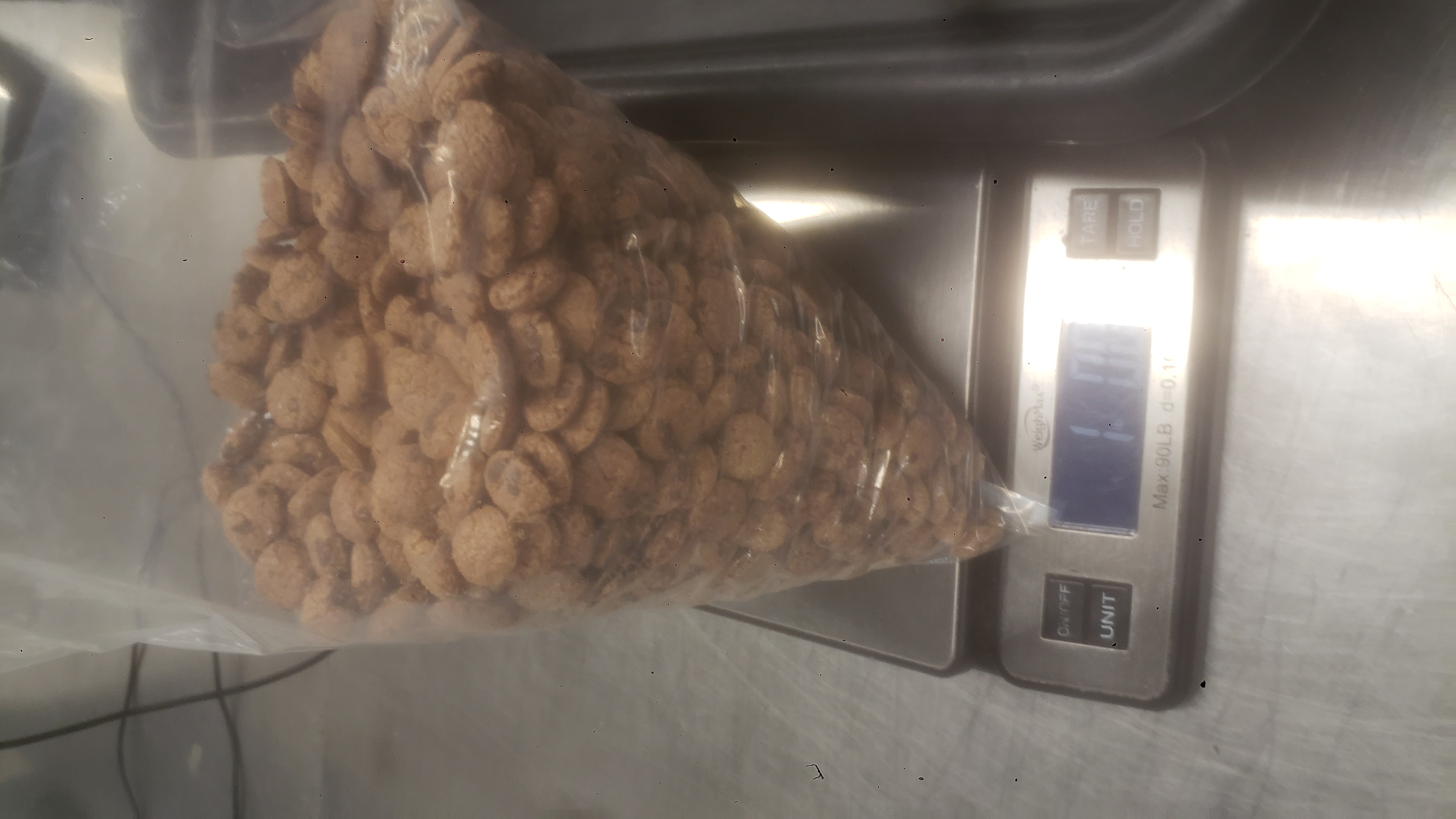 Bag of cookie crisps on a weighted scale that reads one pound and one ounce.